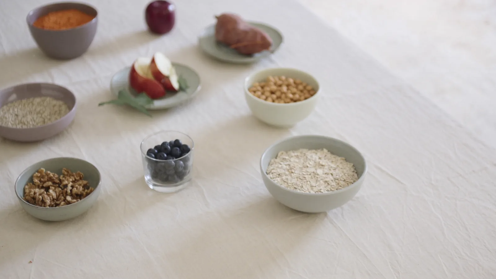 Vue de dessus de bols de lentilles, de quinoa, de flocons d'avoine, de pois chiches et de myrtilles sur une nappe en lin